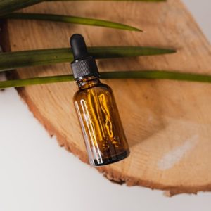 Essential oil bottle lying on wood block with tea tree leaves